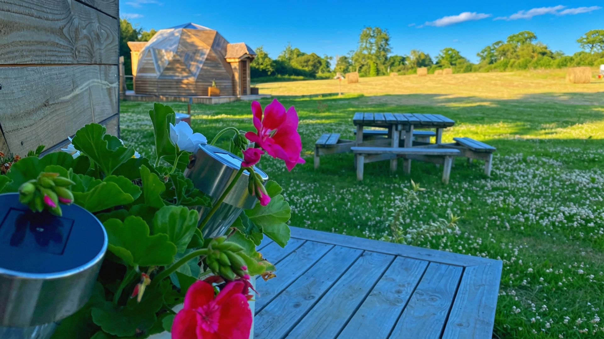 Dôme en bois derrière un massif de fleurs sur la terrasse
