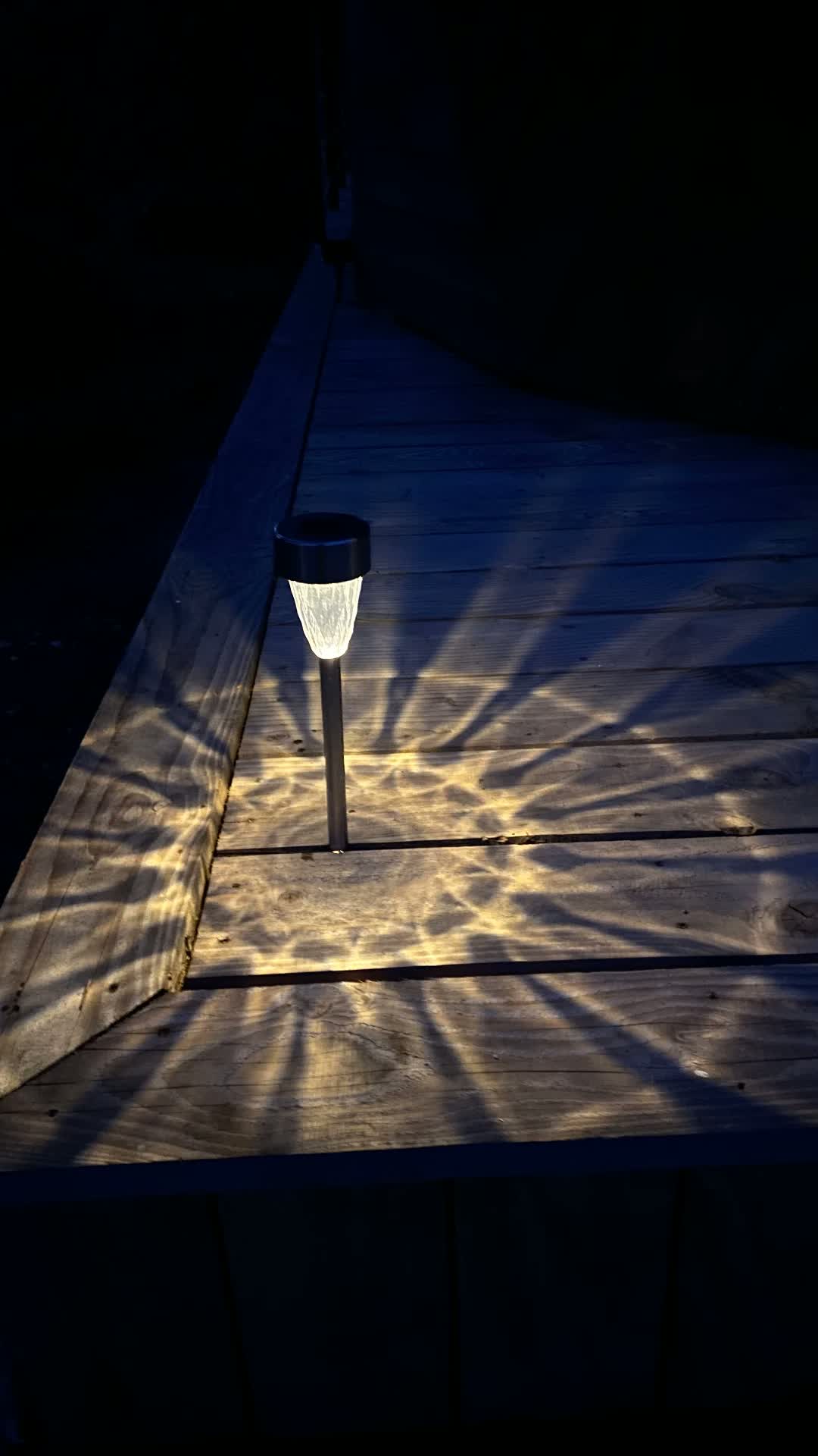 Lanterne solaire projetant une étoile de lumière sur la terrasse
